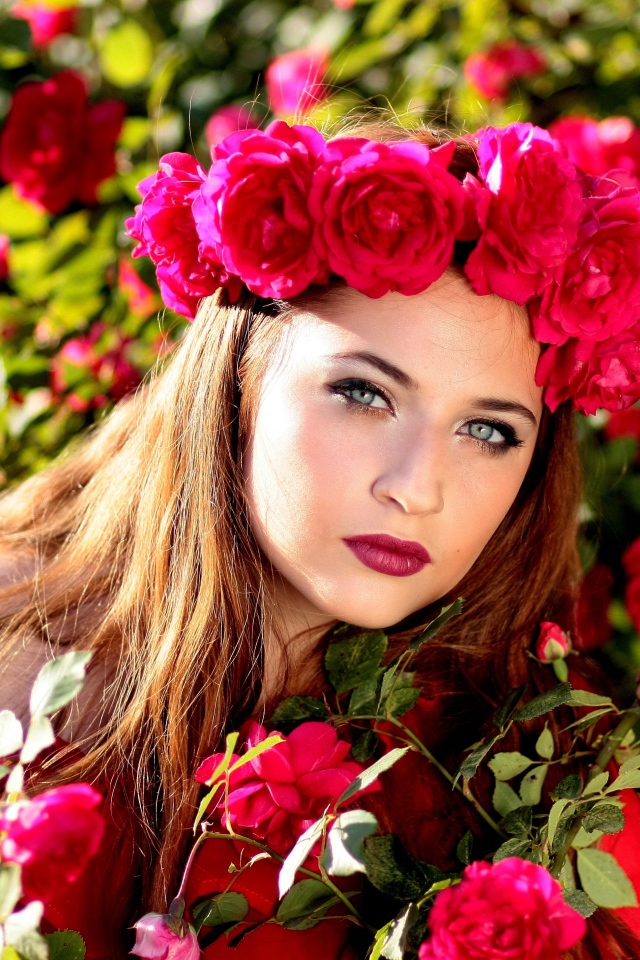 Красивая девушка с венком из красных роз на голове 