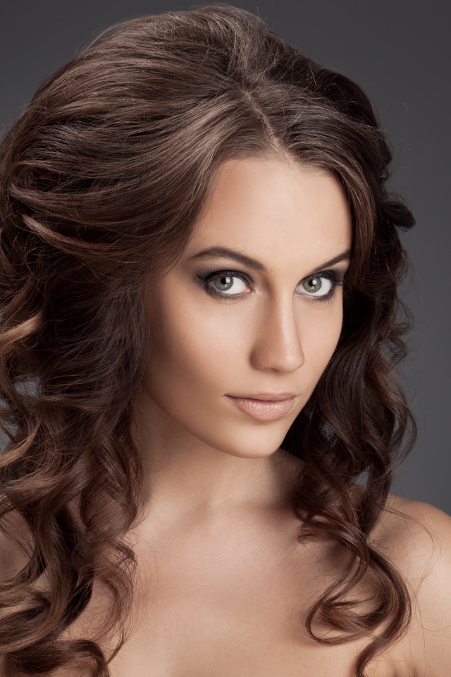 Красивая девушка с волнистыми волосами фото на сером фоне