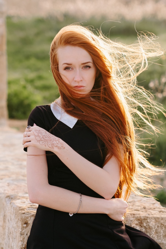 Красивая рыжеволосая девушка в черном платье с рисунком на руке