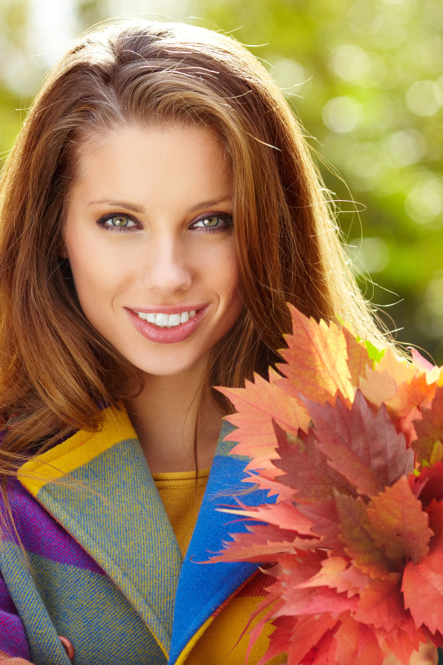 Красивая улыбающаяся девушка с букетом желтых листьев в руке