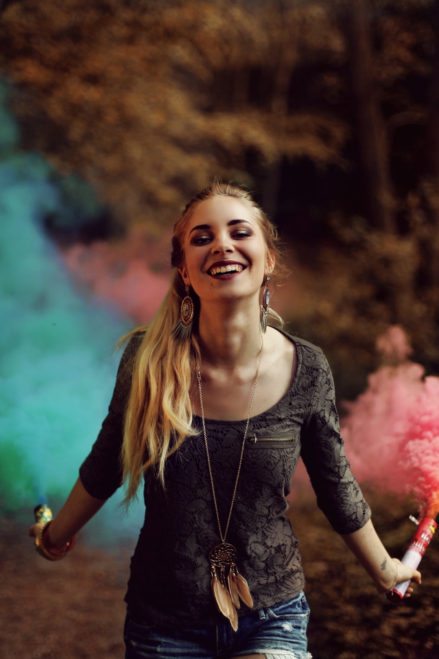 Красивая улыбающаяся девушка с дымовыми шашками в руках