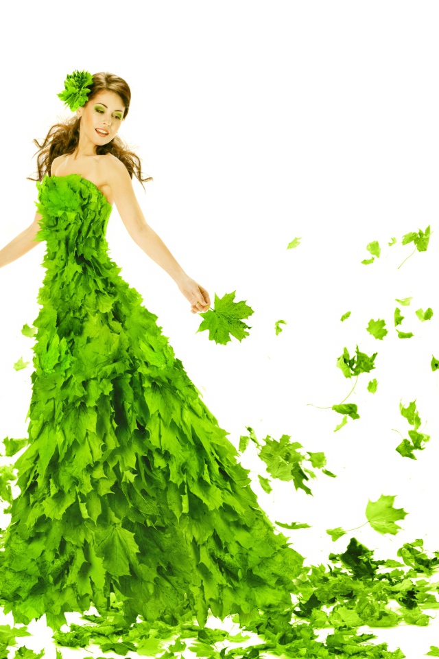 Красивая молодая девушка в платье из зеленых листьев на белом фоне