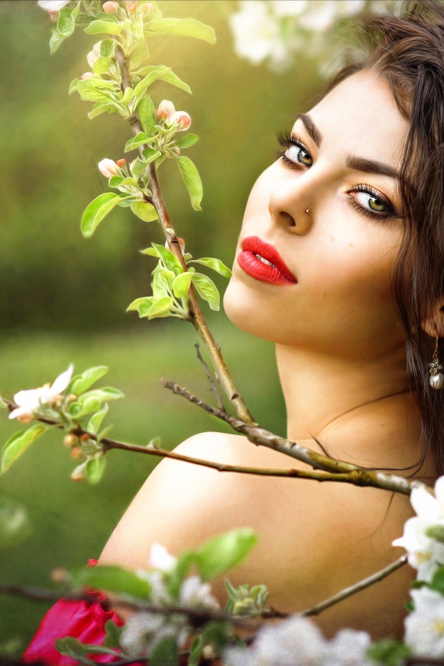 Красивая молодая девушка в ветках цветущей яблони 