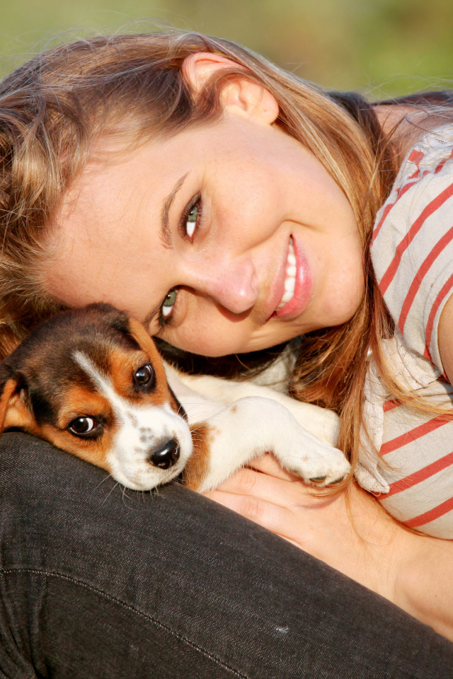 Убающаяся девушка шатенка с милым щенком на руках