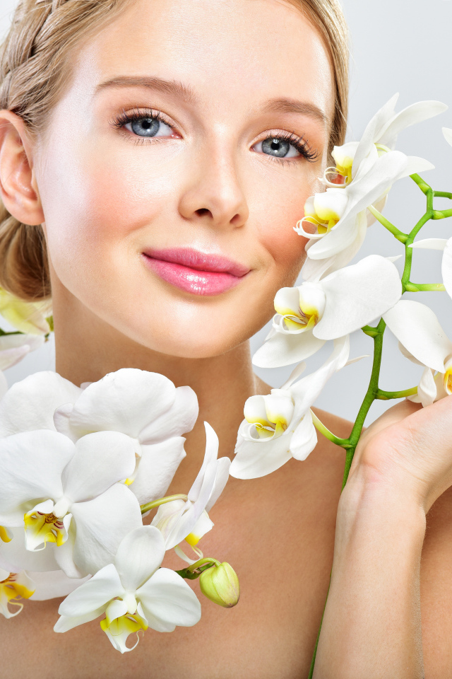 Нежная голубоглазая девушка с цветами орхидеи в руках