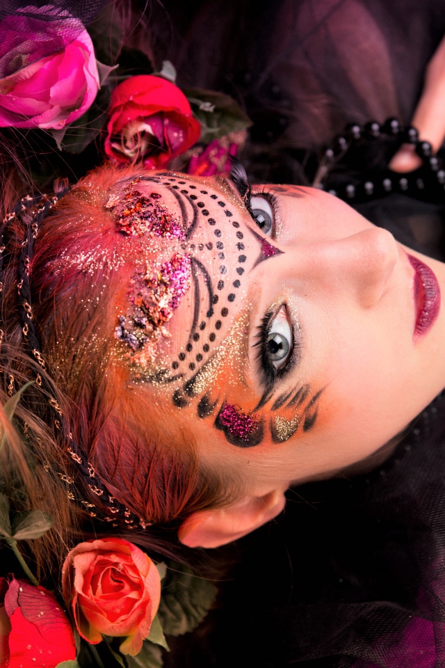 Девушка с блестящим ярким макияжем и розами в волосах