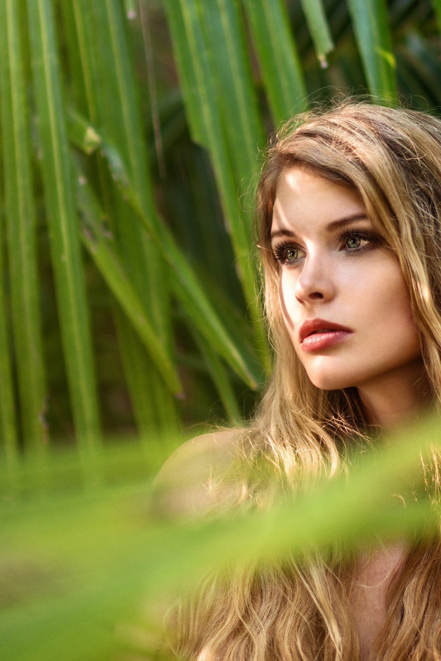 Девушка с волнистыми волосами в пальмовых листьях 