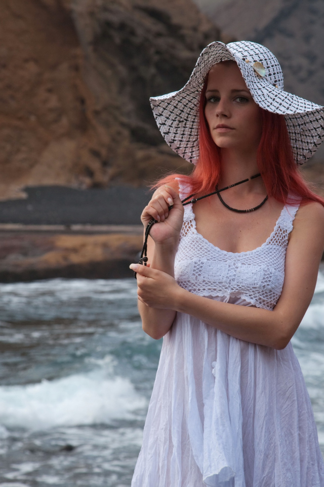 Рыжеволосая девушка в шляпе и белом платье у реки