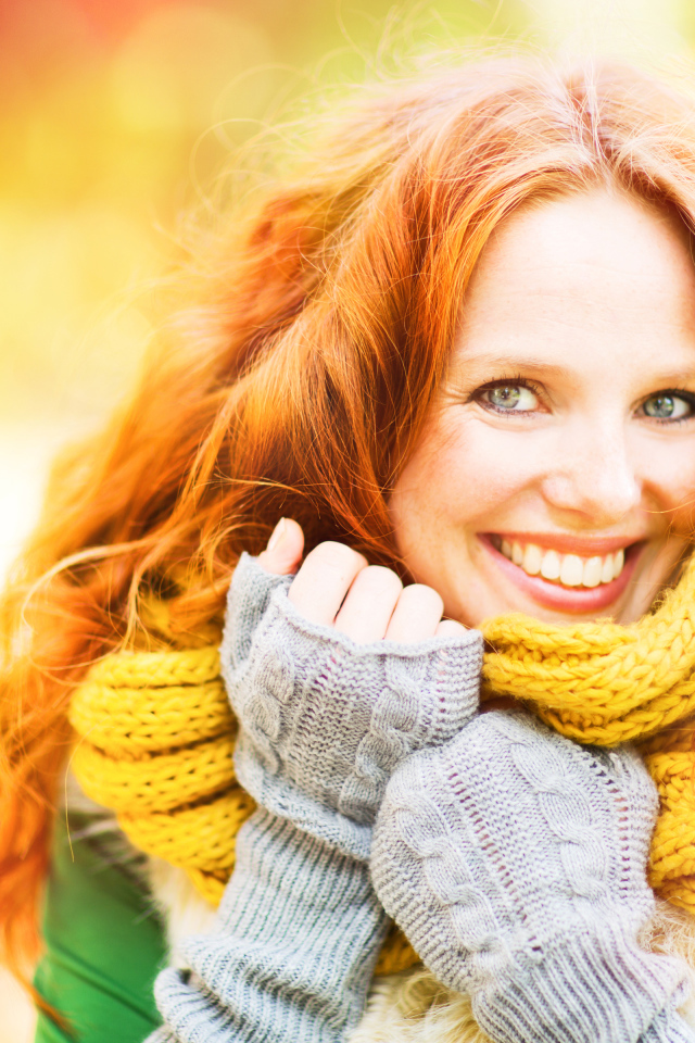 Улыбающаяся рыжеволосая девушка в теплом шарфе