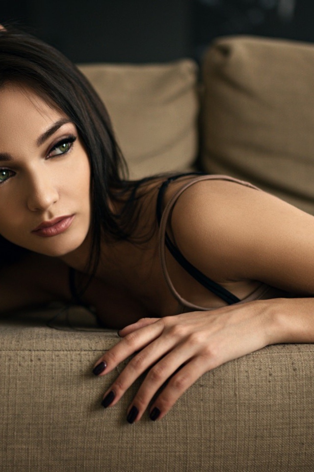 Эффектная молодая девушка лежит на диване 