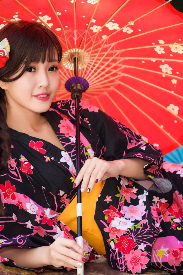 Молодая азиатка в кимоно с разноцветными зонтиками