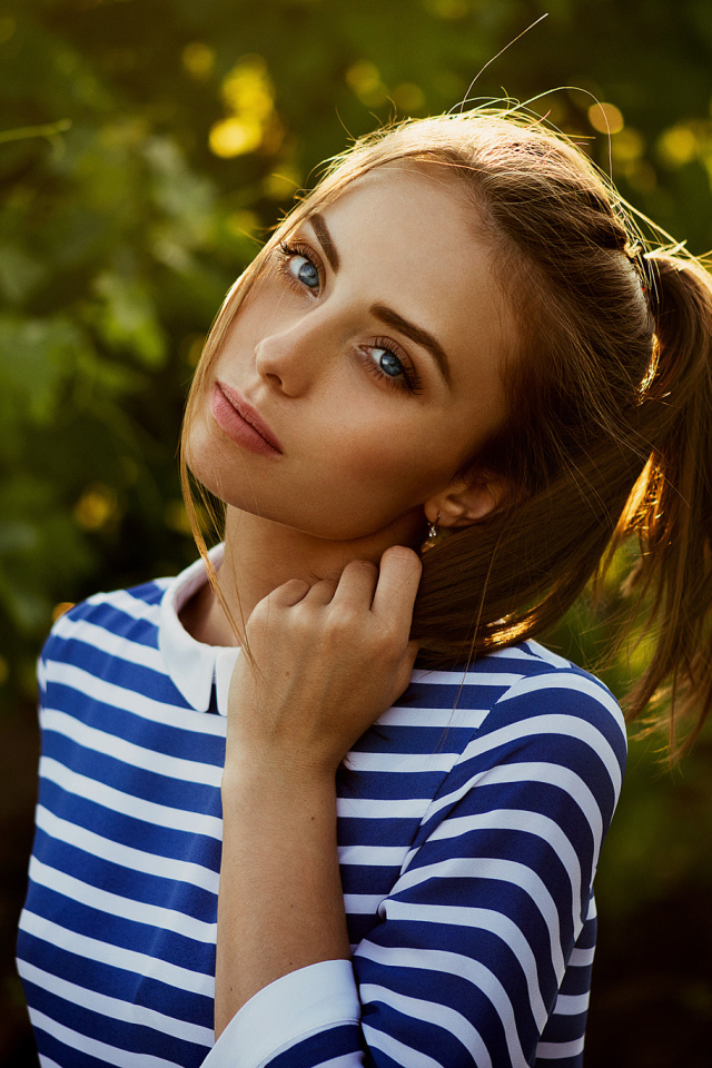Молодая голубоглазая девушка в полосатом платье