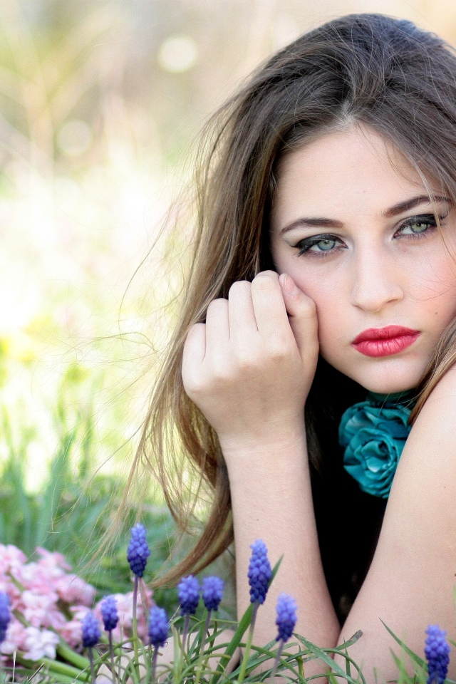 Молодая девушка брюнетка с голубыми глазами лежит на траве 