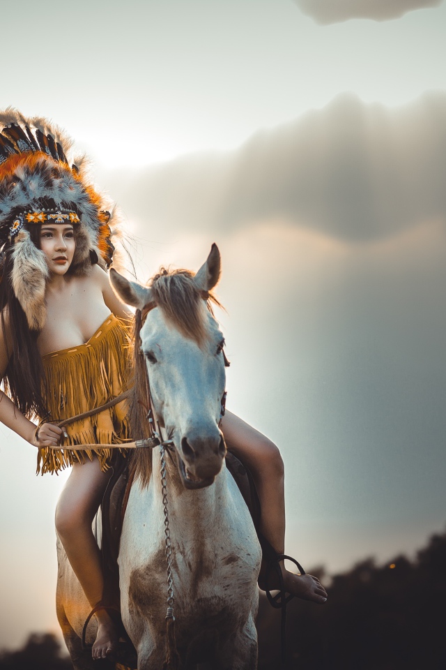 Молодая девушка в костюме индейца на коне
