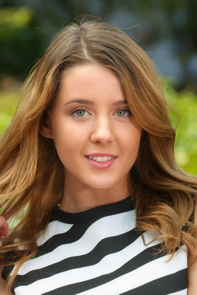 Молодая улыбающаяся девушка в полосатом платье