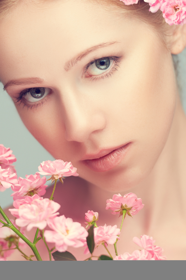 Молодая нежная девушка с розовыми розами на сером фоне