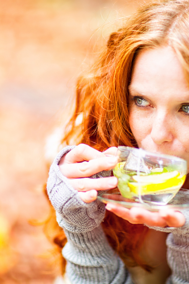 Рыжеволосая девушка модель с чашкой зеленого чая 