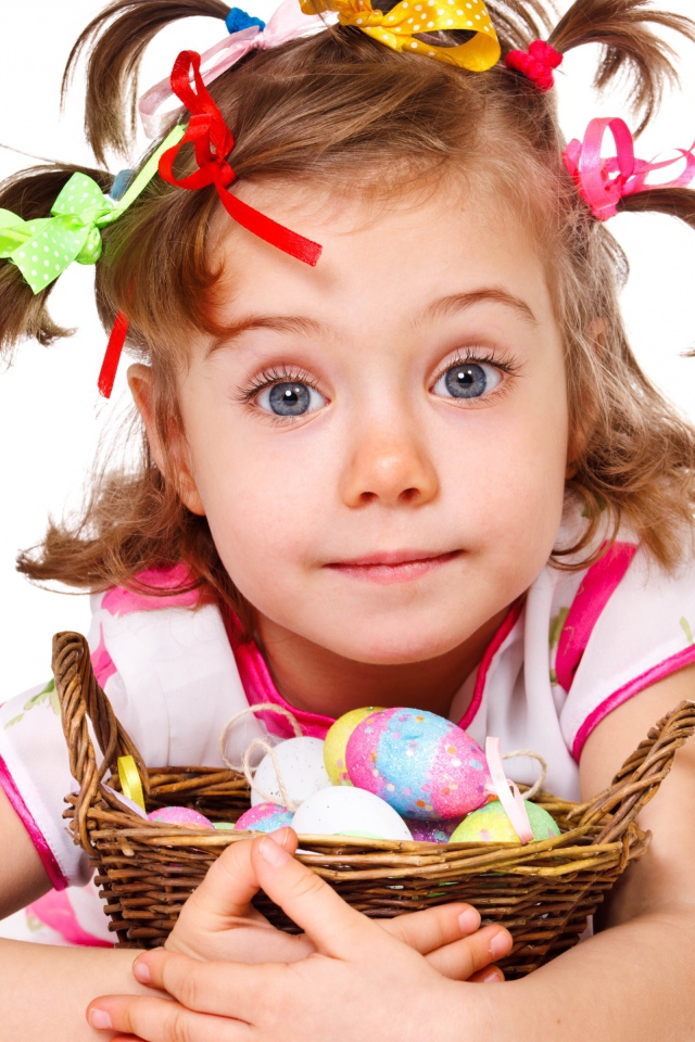 Маленькая девочка с корзинкой пасхальных яиц на белом фоне 