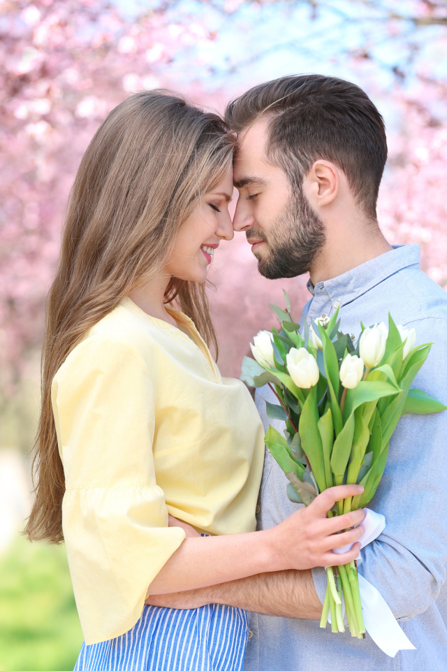 Влюбленная пара стоит в цветущем парке