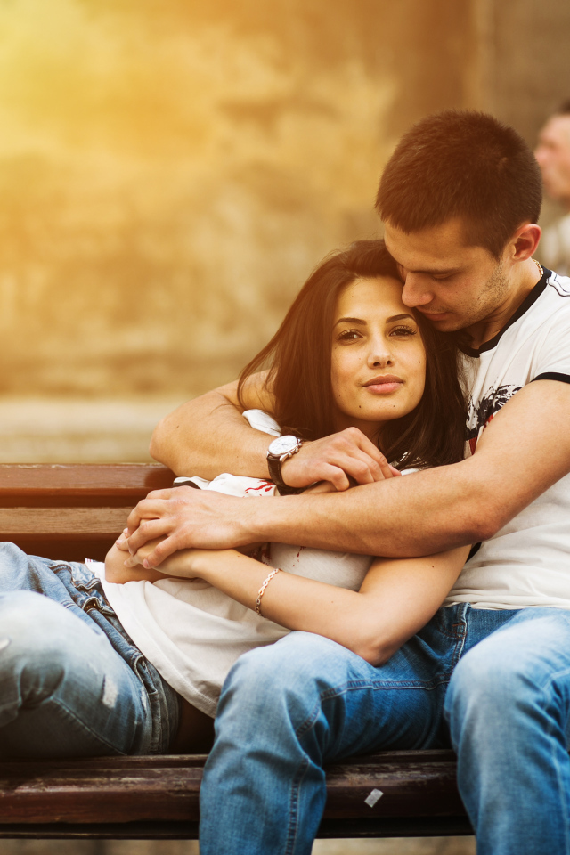 Влюбленная пара сидит на деревянной лавке в парке