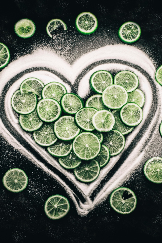 Сердце из сахара и кружочков  зеленого лайма на черном фоне