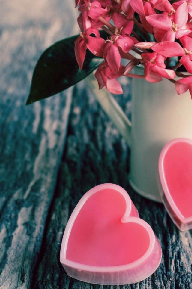 Розовые цветы в белой вазе и два розовых сердца 
