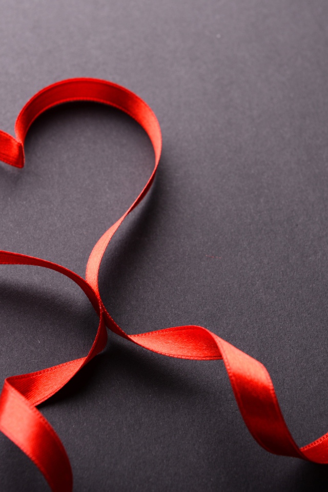 Красное сердце из атласной ленты на сером фоне