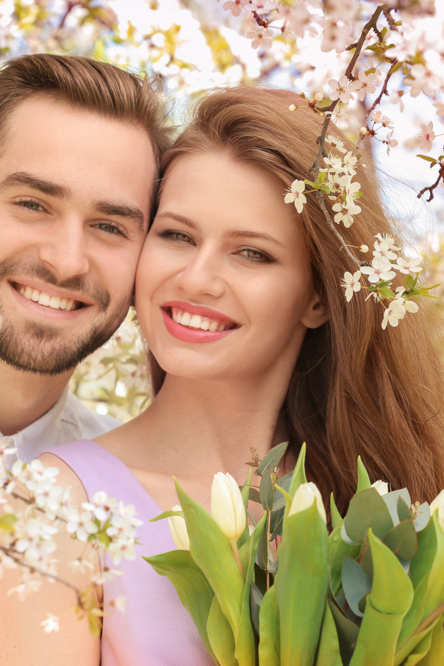 Улыбающаяся влюбленная пара у цветущего дерева