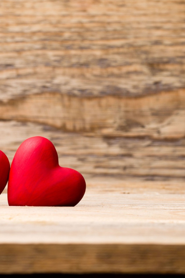 Два красных сердца лежат на деревянной лавке
