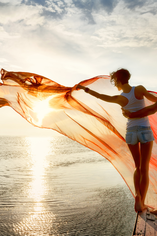 Молодая влюбленная пара гуляет у моря на закате