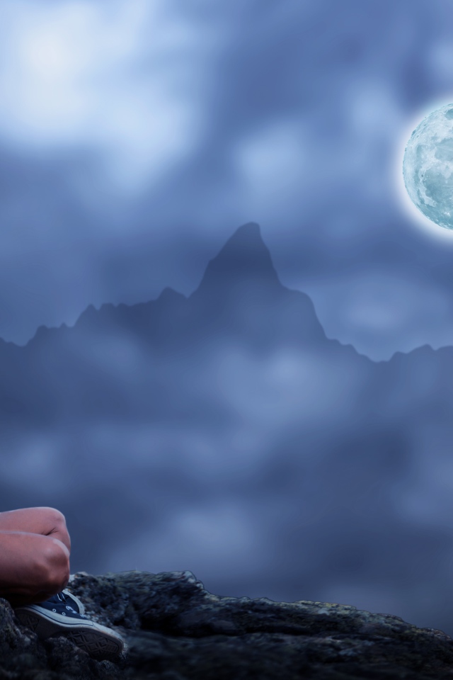 Мужчина медитирует на камне ночью в полнолуние