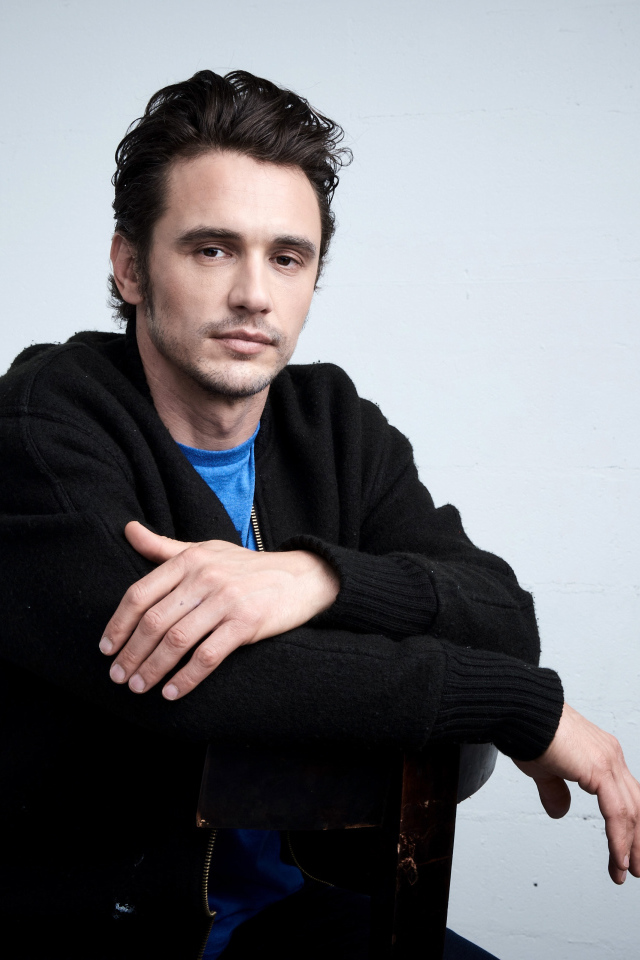 Актер Джеймс Франко в черной кофте на сером фоне