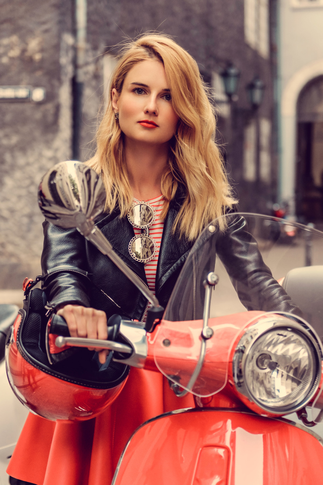 Beautiful blonde girl in a black jacket on a red motorcycle