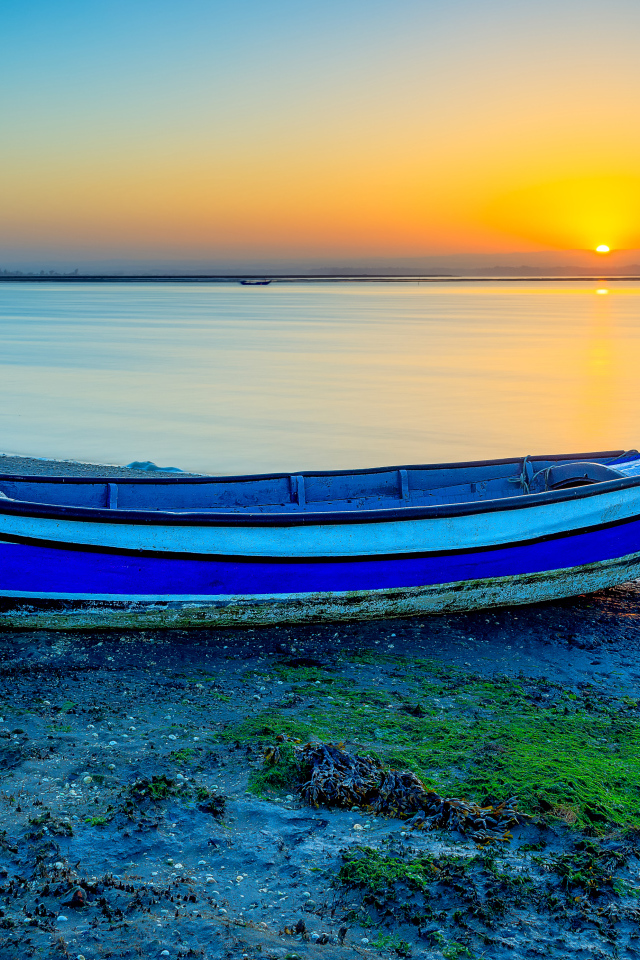 Лодка на берегу реки на закате солнца