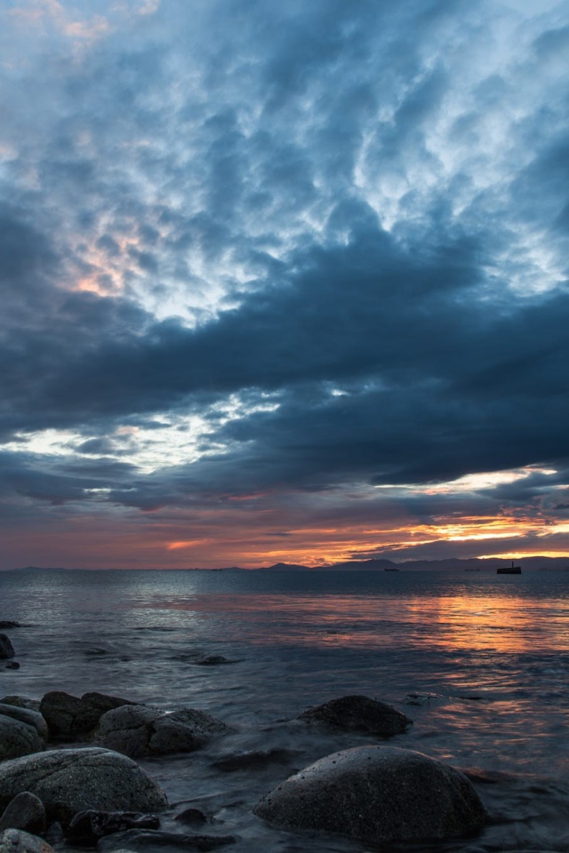 Валуны в воде на берегу на фоне пасмурного неба 