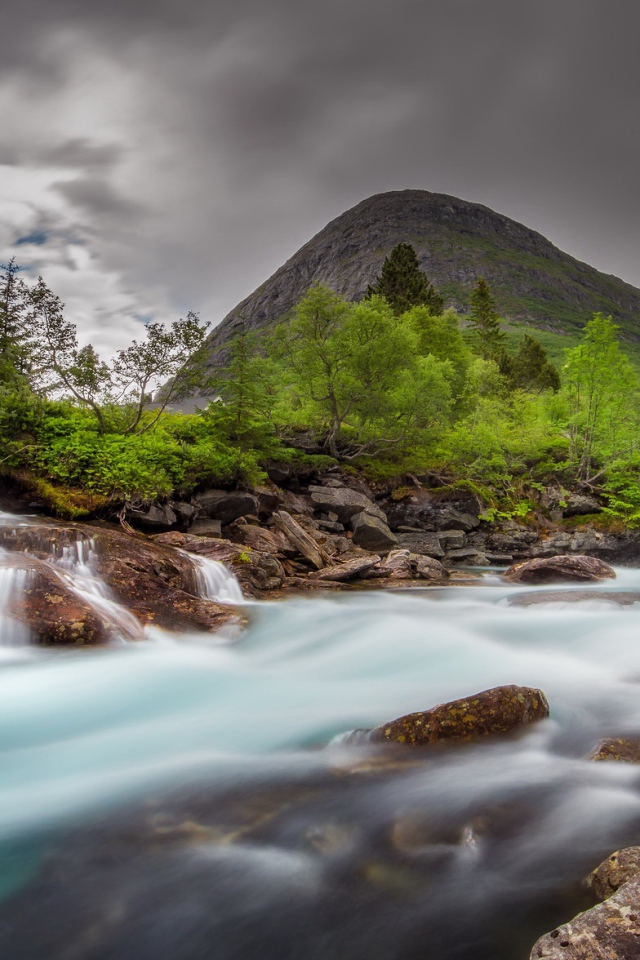 Быстрая вода в горной реке с маленьким водопадом 