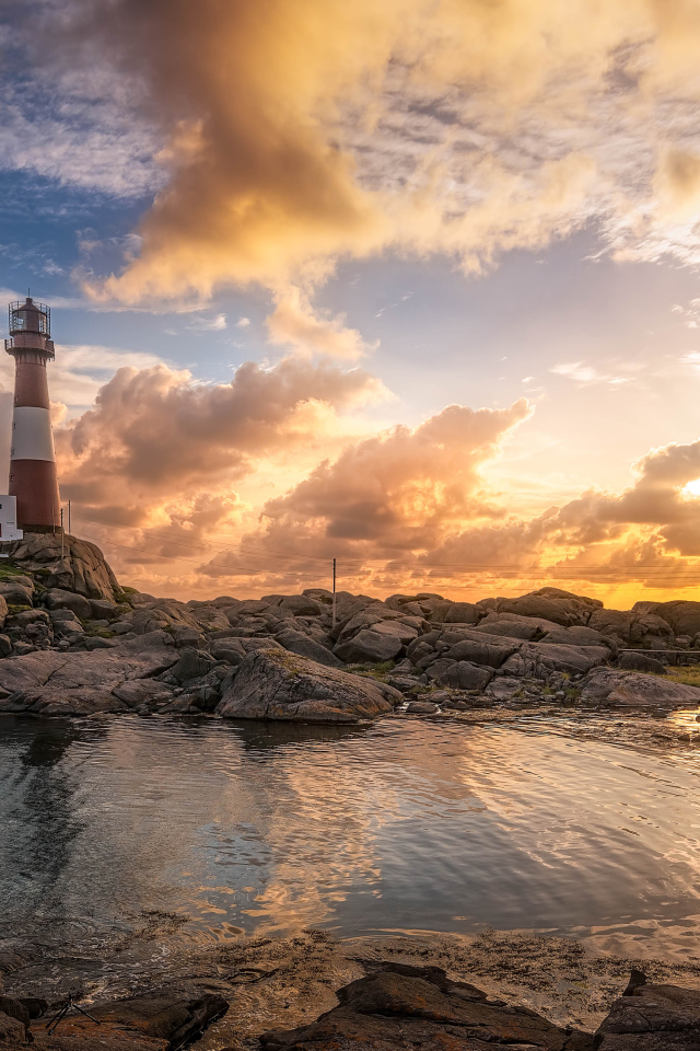 Маяк на каменном побережье на фоне красивого неба