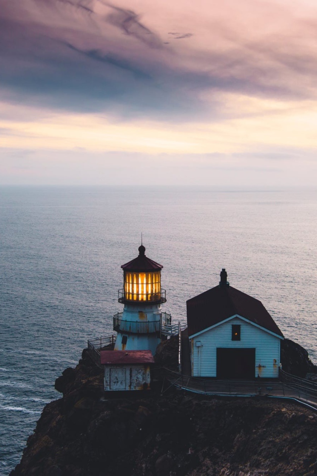 Маяк на скале на фоне горизонта океана 