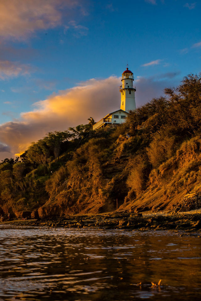 Маяк на склоне скалы на закате 