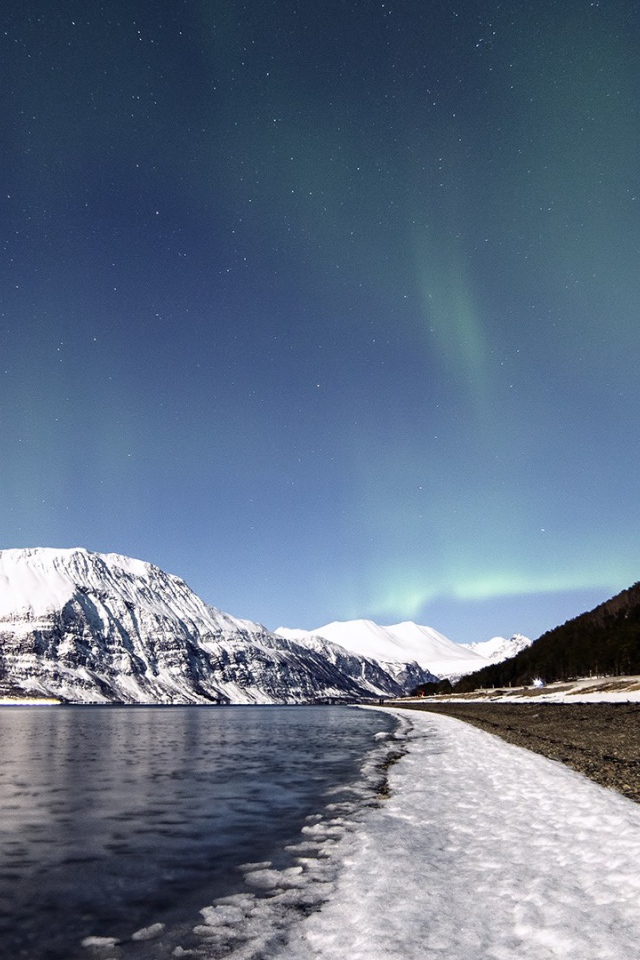 Северное сияние в небе над заснеженными горами 