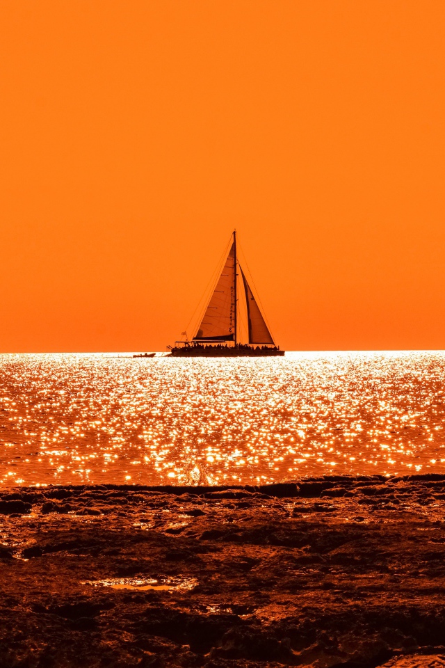 Парусная лодка на горизонте в океане на закате солнца