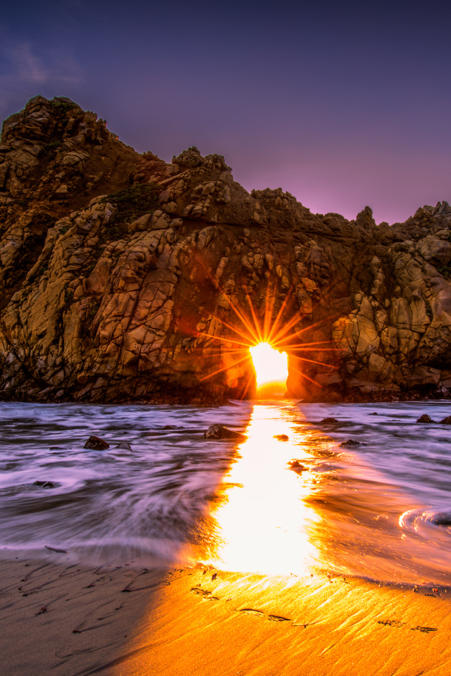 Лучи солнца пробиваются сквозь отверстие в скале  Pfeiffer Beach Big Sur, Калифорния  
