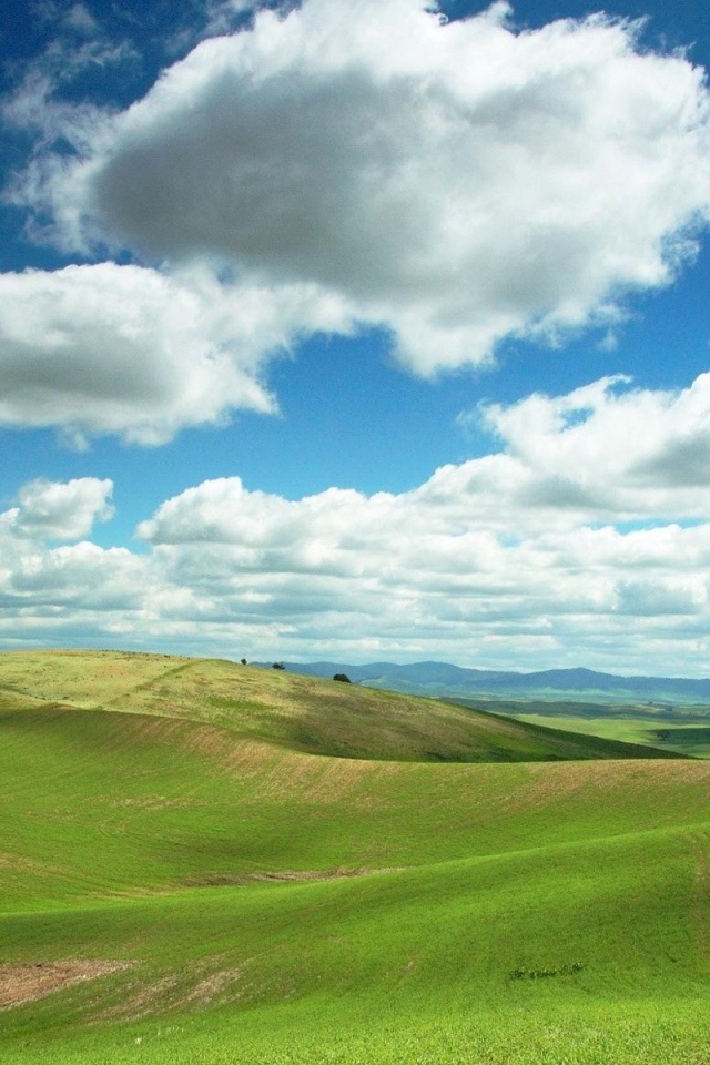 Белые облака в голубом небе над зеленой равниной