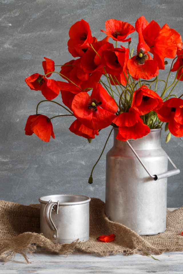 Букет красных маков в железном бидоне на столе с кружкой