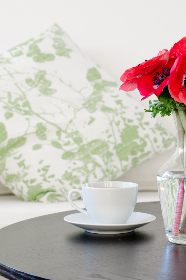 Букет красных цветов анемоны в вазе на столе с белой чашкой