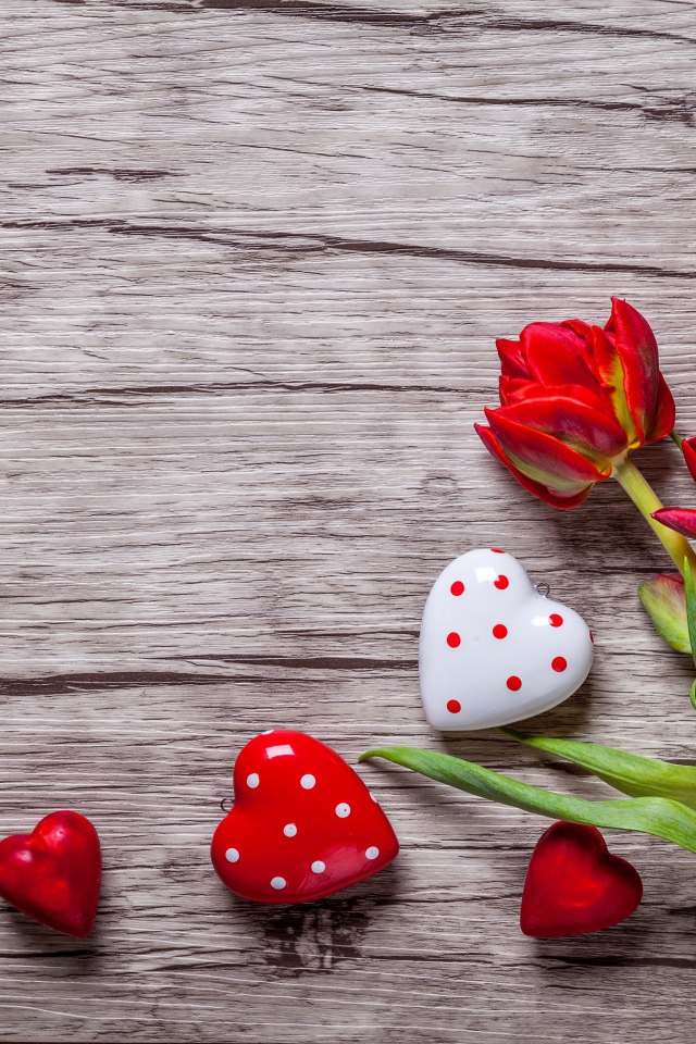 Красные красивые тюльпаны с сердечками на деревянной поверхности