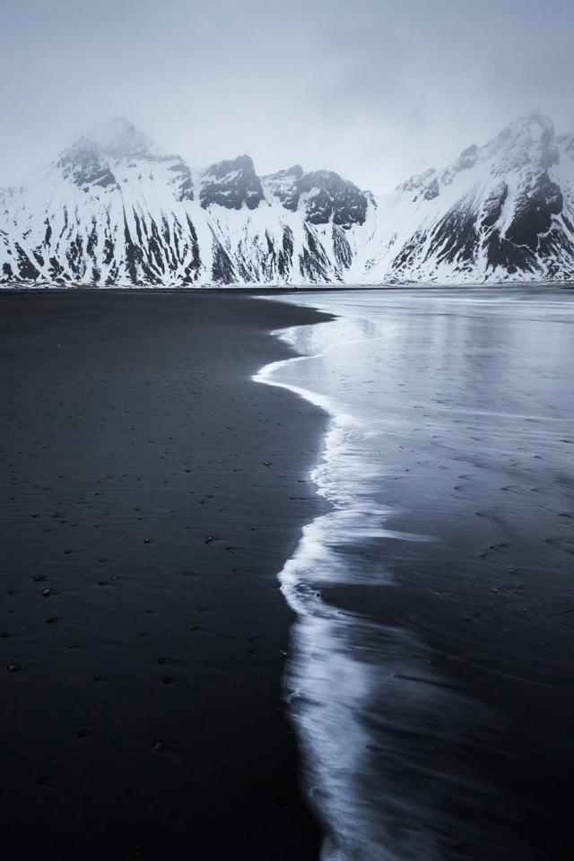Заснеженные горы у пустынного пляжа