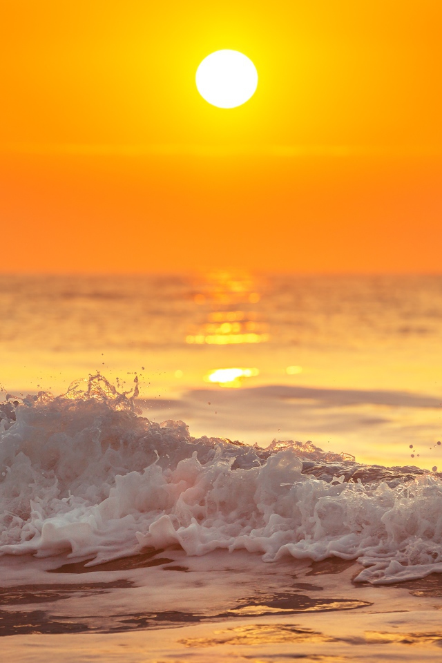 White foam on the seashore in the sunlight at sunset