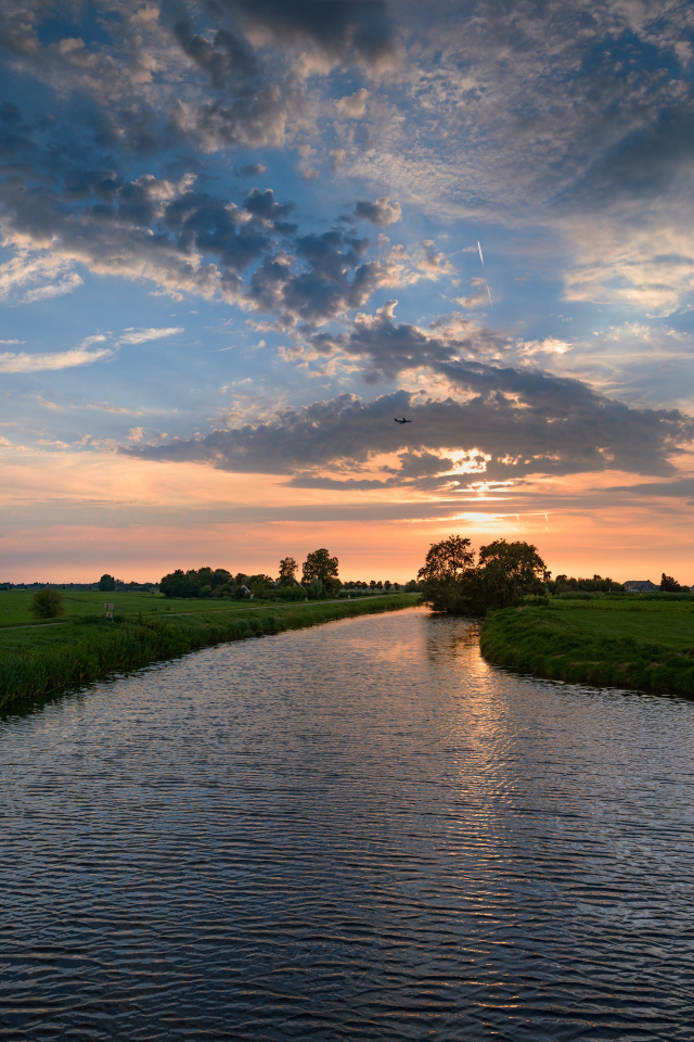 Закат солнца в облаках  над спокойной рекой