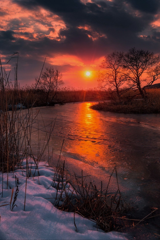 Закат солнца над покрытой льдом рекой